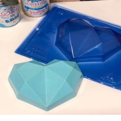 Forma de silicone azul e objeto em forma de coração azul claro sobre superfície branca com frascos ao fundo