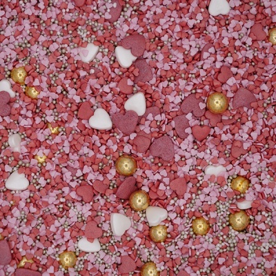 Confeitos decorativos para bolos em tons de rosa, branco e dourado em forma de coração e pequenas bolas.