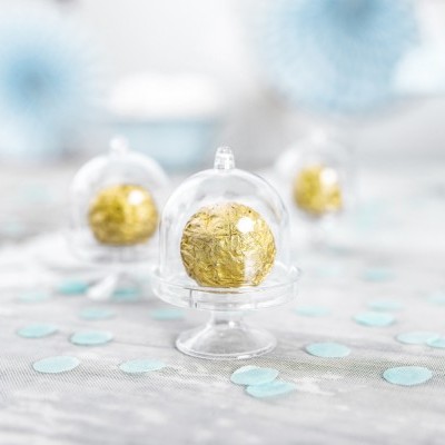 Bolas de chocolate douradas em mini taças de vidro com tampas, sobre mesa decorada com bolas azuis e brancas.