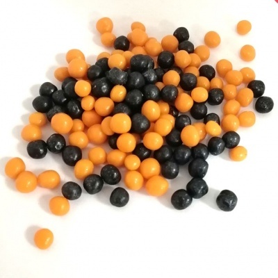 Esferas pequenas laranja e pretas sobre superfície branca