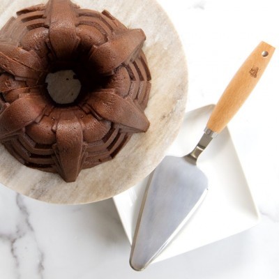 bolo de chocolate em forma de coroa numa tábua de madeira com espátula