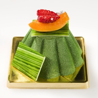 Sobremesa fina verde com textura aveludada, frutas e decoração num prato dourado