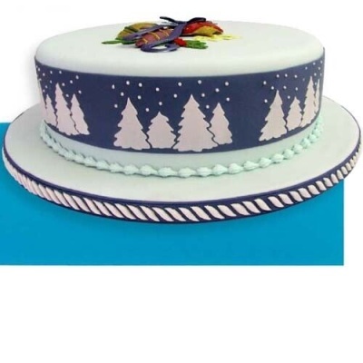 Bolo decorado com faixa de pinheiros brancos sobre fundo azul escuro e topo branco com decoração colorida