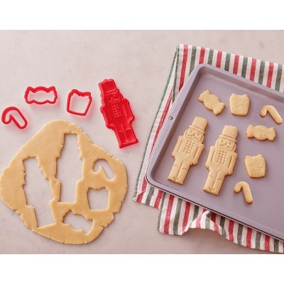 Conjunto de cortadores de biscoitos vermelhos com massa estendida e biscoitos moldados numa forma