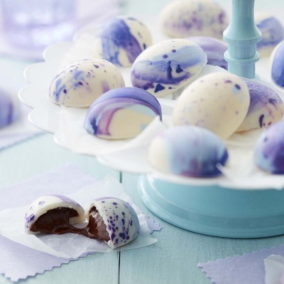 Bombons de chocolate branco com manchas roxas e recheio de chocolate.