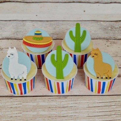 Cinco cupcakes decorados com cactos, sombrero e lhamas em copos coloridos
