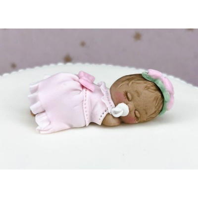 Boneca bebé dorminhoca com vestido rosa claro, chupeta e faixa verde e rosa no cabelo