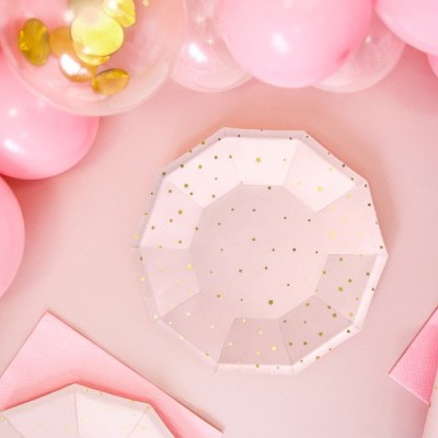 Conjunto de festa com pratos e copos brancos com estrelas douradas, palhinhas douradas, guardanapos cor-de-rosa e balões cor-de-rosa e dourados.