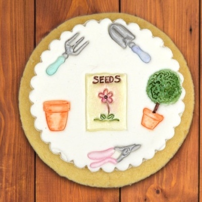 Bolo decorado com tema de jardim sobre mesa de madeira