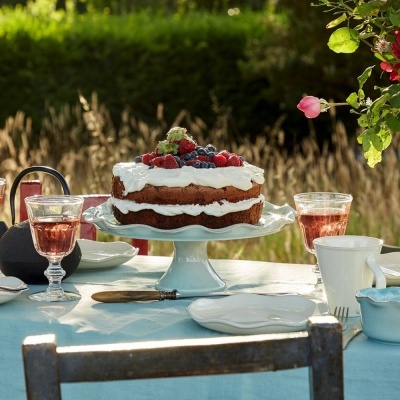 Bolo de chocolate com creme e frutos vermelhos numa mesa ao ar livre com utensílios de chá