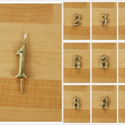Velas douradas em forma de números de 0 a 9 sobre madeira clara