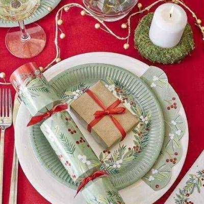 Mesa posta com loiça decorada, vela, caixa de presente castanha com fita vermelha e toalha de mesa vermelha