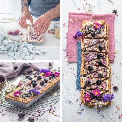Tarte decorada com amoras, flores comestíveis, amêndoas e chocolate num ambiente de cozinha