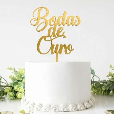 Bolo branco com topper dourado 'Bodas de Ouro' e folhagem verde como decoração