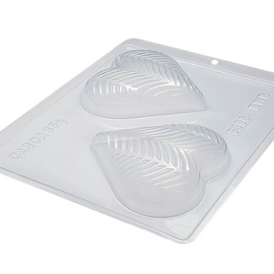 Forma de moldar chocolate em plástico transparente com dois corações com padrão de folhas.