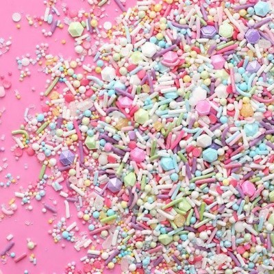 Granulado colorido em tons pastel sobre fundo rosa