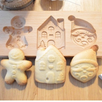 Moldes de madeira para biscoitos com formas natalícias e biscoitos assados