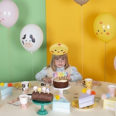 Festa infantil com menina loira, balões de vaca e pintainhos, bolo chocolate com velas HAPPY e bolos decorados em tons pastel