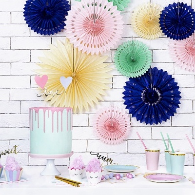 Decoração de festa com bolo drip azul claro e rosa, cupcakes, pratos e copos pastel, leques de papel coloridos