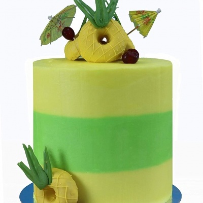 Bolo cilíndrico amarelo e verde com decoração de ananás, frutas vermelhas e mini guarda-sóis de papel