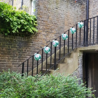 Escada exterior com bolas de futebol penduradas no corrimão e vegetação