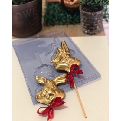 Molde transparente com chocolates em forma de coelhos dourados com laço vermelho