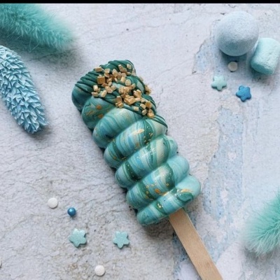 Gelado em espiral azul turquesa com chocolate verde escuro e pedaços dourados em fundo claro