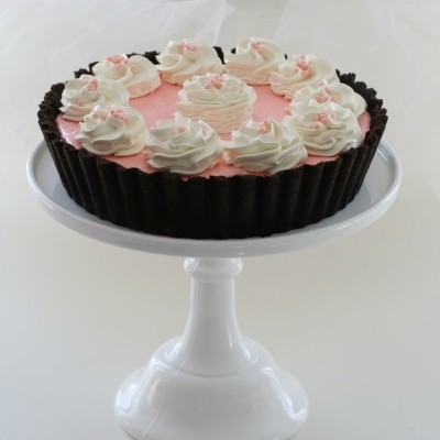 Tarte rosa com chantilly branco em suporte branco