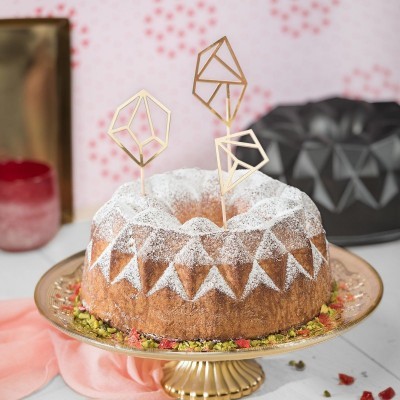 Bolo redondo decorado com açúcar e topos geométricos dourados num prato dourado