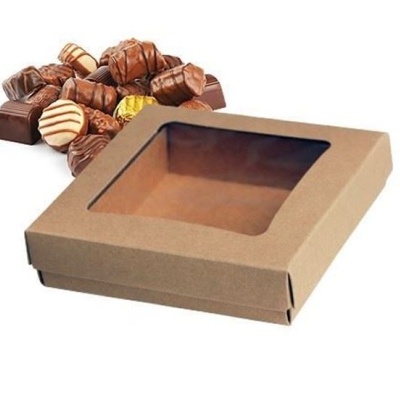 Caixa de cartão castanho com tampa transparente para chocolates e vários bombons à volta