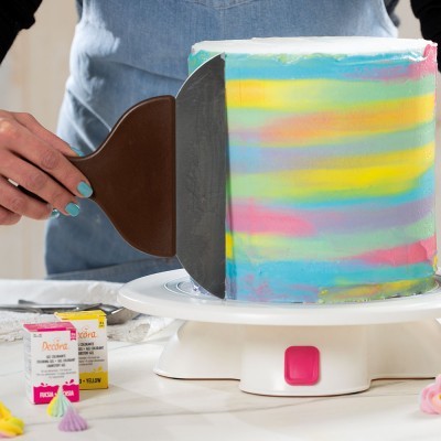 Bolo quadrado com glacê colorido tie-dye em processo de alisamento com espátula