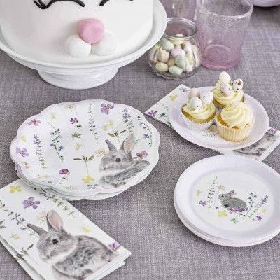 Conjunto de pratos e guardanapos com coelhos e flores, bolo decorado como coelho e cupcakes com ovos sobre toalha cinzenta