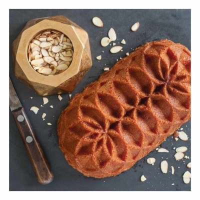 Bolo com padrão floral, tigela dourada com lascas de amêndoa, faca com cabo de madeira