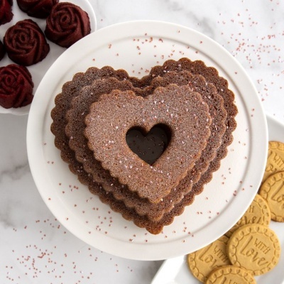 Biscoitos em forma de coração empilhados e biscoitos redondos com a inscrição 'WITH LOVE' e trufas de chocolate ao fundo