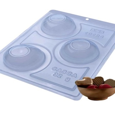 Molde transparente com três cavidades redondas para chocolate e pequeno recipiente com doces.