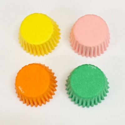 Quatro formas de papel para cupcakes coloridas: amarelo, rosa, laranja e verde.