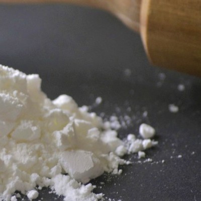 Pó branco e cilindro de madeira num fundo escuro