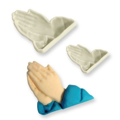 Três moldes de silicone em forma de mãos a fazer prece, dois em branco e um preenchido com material castanho claro e azul.