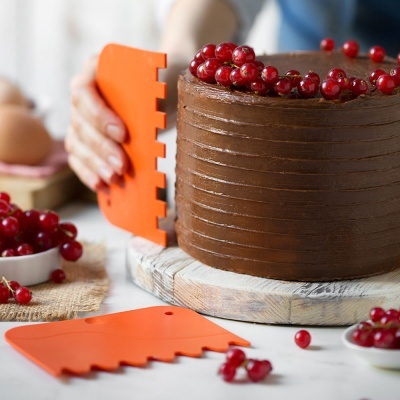 Bolo de chocolate decorado com groselhas e ferramentas laranja de confeitaria para texturizar o bolo