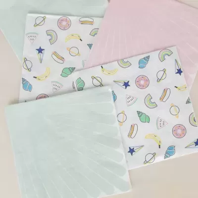 Guardanapos de tecido com padrões coloridos e dois guardanapos lisos em tons pastel.