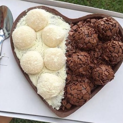 Caixa de chocolate em forma de coração com brigadeiros brancos e de chocolate.