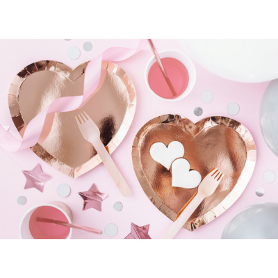 Pratos coração cobre metálico com garfos de madeira e decoração em superfície rosa.