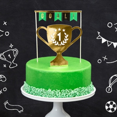 Bolo verde com topper de troféu dourado e bandeiras 'GOAL!' em fundo preto com desenhos de futebol