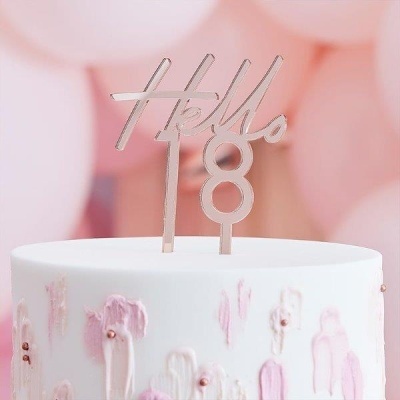 Bolo branco com decoração rosa e dourada e topper prateado com texto 'Hello 18'