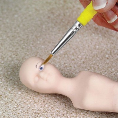 Pincel a pintar olho de figura de porcelana num fundo bege