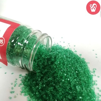 Cristais verdes granulares derramados de um frasco transparente