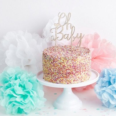 Bolo redondo com granulado colorido e topper dourado 'Oh Baby' em suporte branco, rodeado por flores de papel coloridas