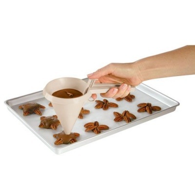 Funil silicone bege para chocolate com nozes pecan em tabuleiro metal
