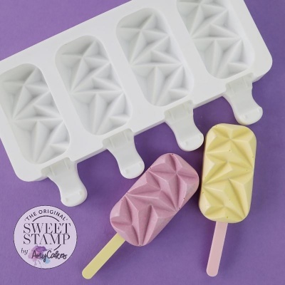 Forma de silicone branca para gelados com padrão geométrico em relevo e dois gelados coloridos rosa e amarelo em pauzinhos