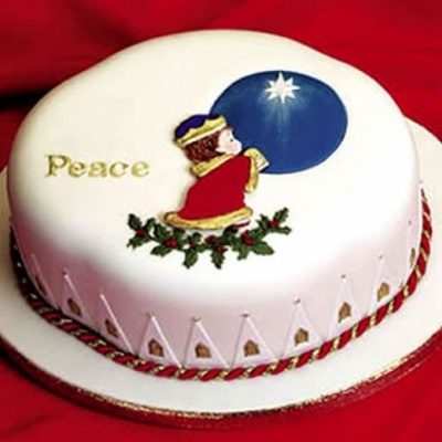 Bolo redondo decorado com criança ajoelhada, círculo azul com estrela branca, palavra 'Peace' em dourado